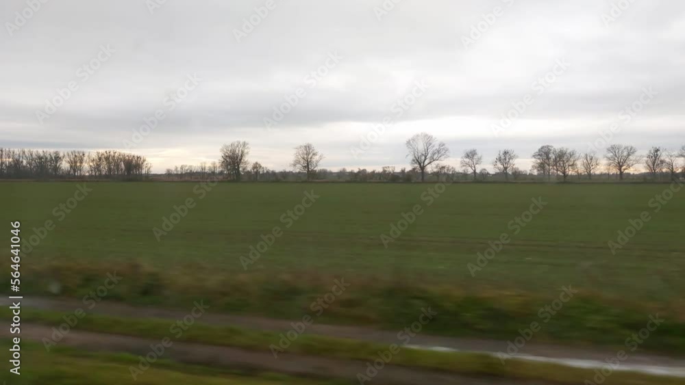 View from the window of a moving train on green fields on a cloudy spring day. View from the window of a moving train on green fields on a cloudy spring day.