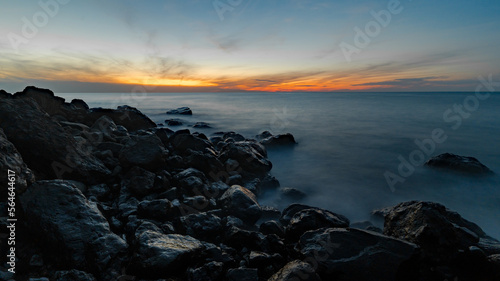 Wide angle long exposure shot of sunset at sea. Coastal rocks in the foreground. Black sea shore. © godbamn