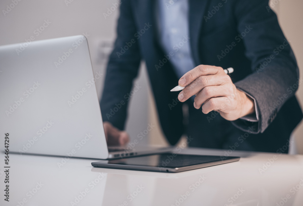 Businessman working with laptop and tablet sitting at the desk. Man write with electronic stylus pen Businessman working with laptop and tablet sitting at the desk. Man write with electronic stylus pen