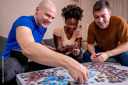 Friends playing jigsaw puzzles at home, on a white wooden table. Putting things together and solving problems. Diversity and fun in a friendship.	
