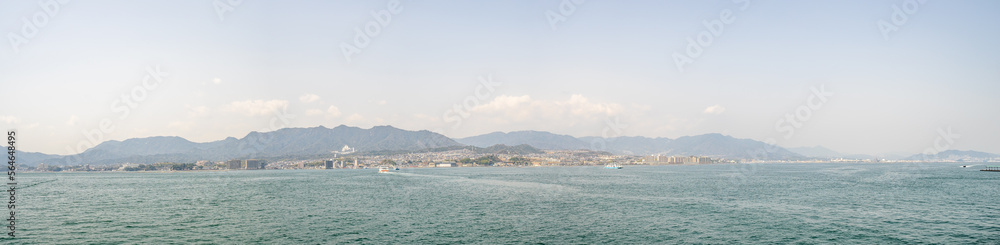 Beautiful panoramic landscape of Miyajima city with ferry boat from the island in Hiroshima prefecture.