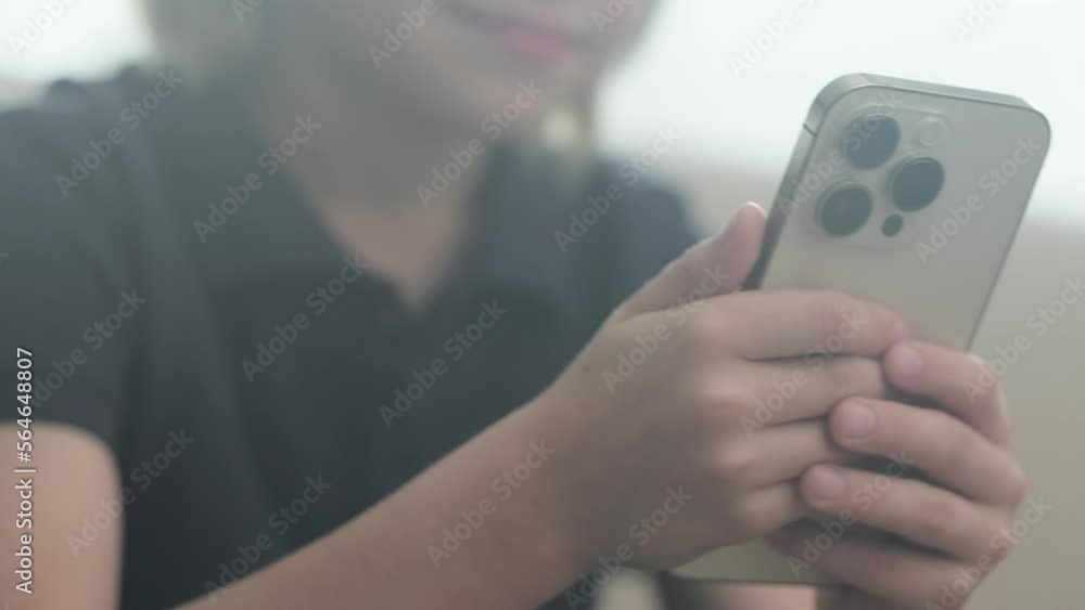 Happy smiling blonde boy using looking phone and sitting home on sofa, holding smartphone two hands. Happy smiling blonde boy using looking phone and sitting home on sofa, holding smartphone two hands.