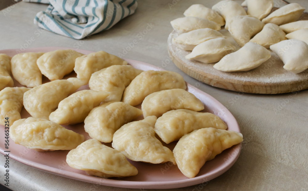 Boiled Vareniks with potato filling on a pink plate. The concept is traditional Ukrainian cuisine. Horizontal orientation.