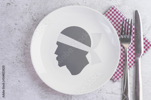 A Plate with the Flag of Corsica, Cutlery and Napkins on the Mable Table. photo