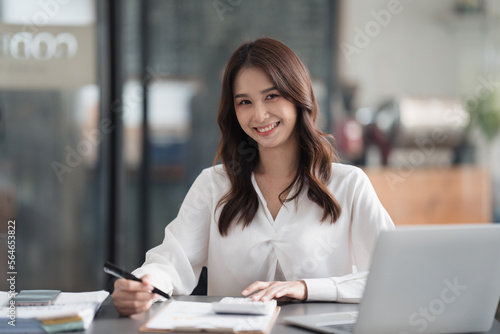 Happy smiling Asian businesswoman working and looking at the camera in office room.
