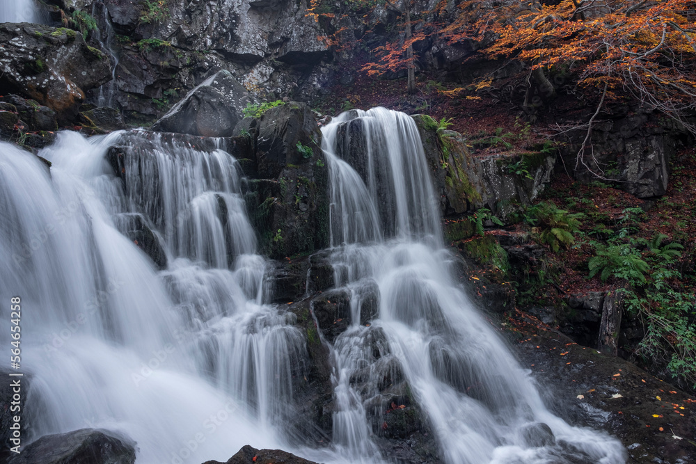 Obraz premium Long exposure of a waterfall in the forest in autum