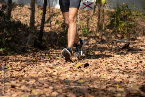 Closeup selective focus of feet runner jogging workout. Marathon runner sport shoes tying shoelace, exercising outdoors workout on forest dirt road. Athlete endurance trail running. © Rakchanok