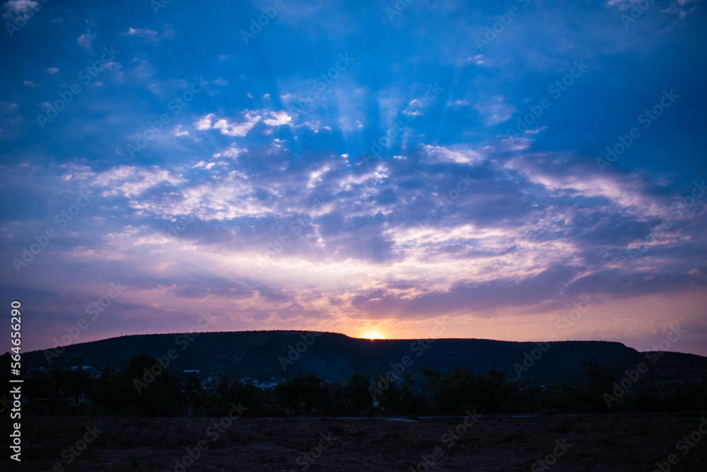 Fotografía de paisaje del cielo color azul con nubes en un amanecer atraves de las montañas