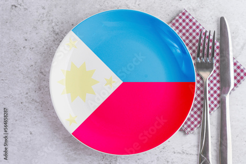 A Plate with the Flag of Philippines, Cutlery and Napkins on the Mable Table. photo