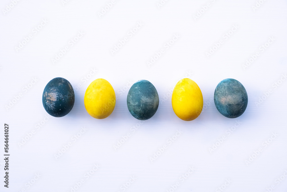 Natural dyed blue and yellow colored eggs on white background, top view, flat lay. Happy Easter. Copy space for text. Natural dyed blue and yellow colored eggs on white background, top view, flat lay. Happy Easter. Copy space for text.