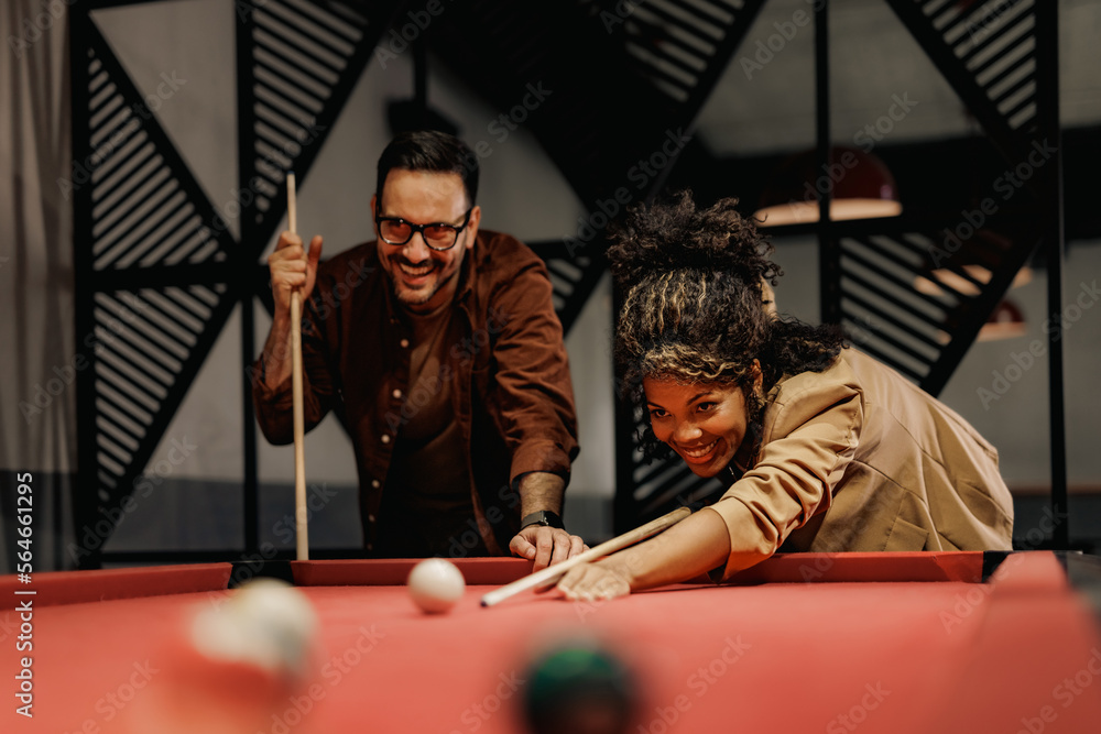 Happy colleagues in love playing billiard together, after a long day at work.
