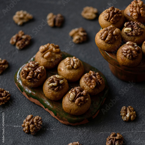 Cookies with walnuts. Soft biscuits shekerpare. Turkish cuisine. Oriental sweets. Baking on ceramic plates on dark surface decorated with nuts. Soft focus. 