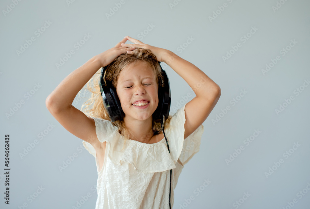 People, music, emotions concept. Delighted carefree female dances in rhythm of melody, closes eyes listens loud song in headphones People, music, emotions concept. Delighted carefree female dances in rhythm of melody, closes eyes listens loud song in headphones