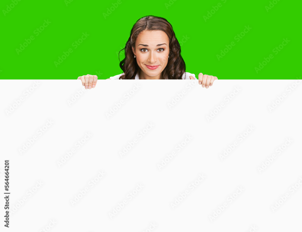 Smiling business woman standing beehind, peeping out white empty mock up signboard. Success and advertising concept. Copy space place. Young businesswoman. Green chroma key background. Smiling business woman standing beehind, peeping out white empty mock up signboard. Success and advertising concept. Copy space place. Young businesswoman. Green chroma key background.
