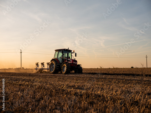 фотографія Tractor plowing and preparing stubble field for crop seeding