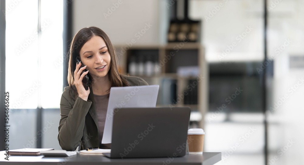 Smiling beautiful Asian businesswoman analyzing chart and graph showing changes on the market and holding smartphone at office. Smiling beautiful Asian businesswoman analyzing chart and graph showing changes on the market and holding smartphone at office.