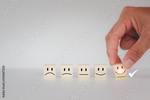 Best excellent business services rating customer experience with Hand of a businessman chooses a smiley face on wood block cube. Satisfaction survey concept. 5 Star Satisfaction.