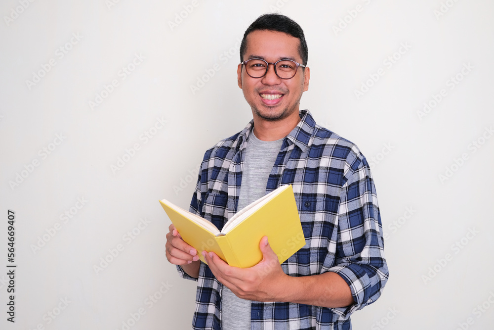 Adult Asian man smiling confident when holding a book Adult Asian man smiling confident when holding a book