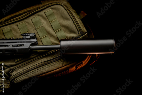 Black silencer for weapons. Suppressor that is at the end of an assault rifle. Weapon close-up. Dark back.