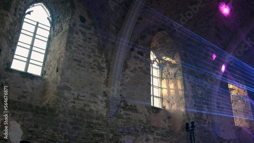 Laser show inside a medieval castle. Rays of laser lights reflecting on old rock wall. Historical building used as entertainment venue for party or concert. 
