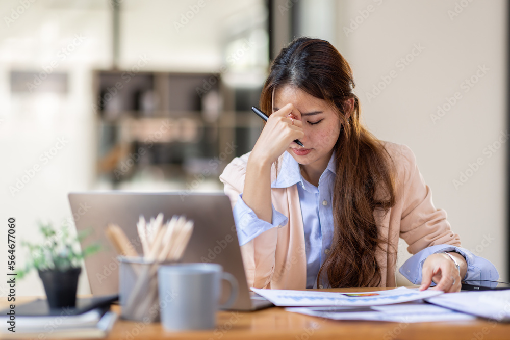Young business Asian women are stressed while working on laptop, Tired asian businesswoman with headache at office, feeling sick at work copy space in workplace an home office. Young business Asian women are stressed while working on laptop, Tired asian businesswoman with headache at office, feeling sick at work copy space in workplace an home office.