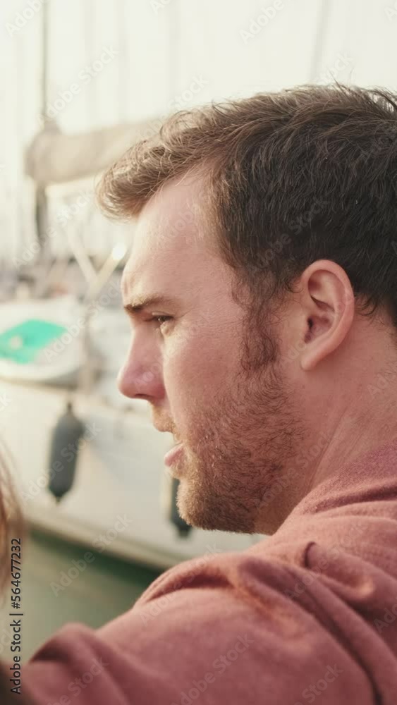 VERTICAL VIDEO: Close up, couple sitting in the port looking at the yachts VERTICAL VIDEO: Close up, couple sitting in the port looking at the yachts
