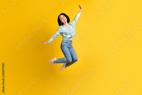Full length photo of satisfied cute gorgeous girl dressed blue cardigan jeans flying having fun isolated on yellow color background