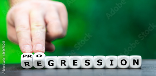 Hand turns dice and changes the word regression to progression.