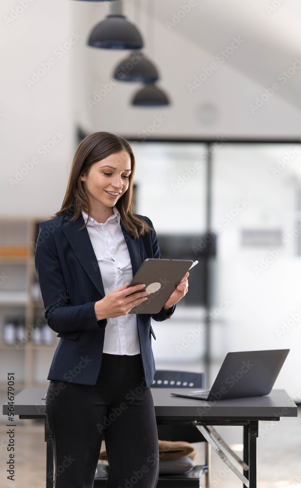 Young asian businesswoman using the tablet to analyze business data while she is standing at the office. Young asian businesswoman using the tablet to analyze business data while she is standing at the office.