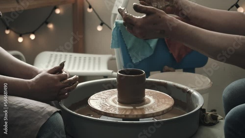 Pottery professional teaches a student how to use potter's wheel. Pottery workshop. Close up hands pottery wheel. Handmade. 