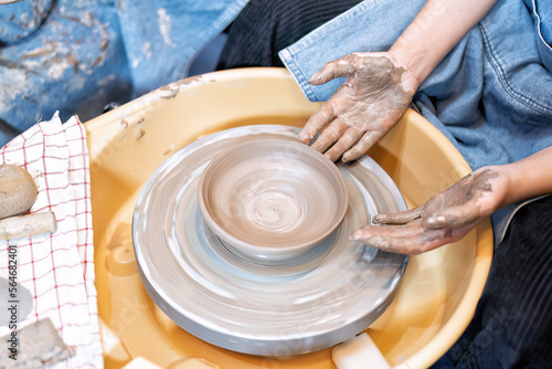 Close up hands make dishes from ceramic clay working on potters wheel traditional pottery craft