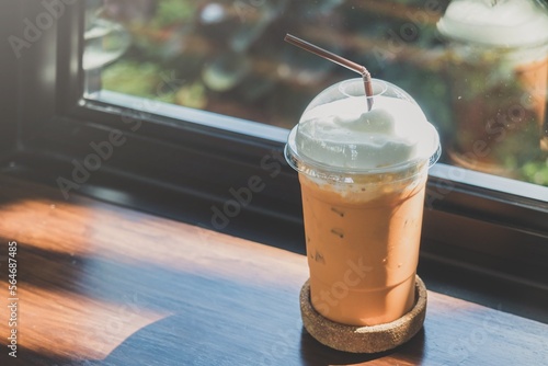 Wallpaper Mural Ice thai milk tea on plastic cup on the wooden bar table with window, blur bokeh background in coffee shop Torontodigital.ca