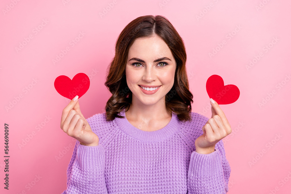 Photo of cheerful shiny lady wear violet sweater rising two little red hearts smiling isolated pink color background Photo of cheerful shiny lady wear violet sweater rising two little red hearts smiling isolated pink color background