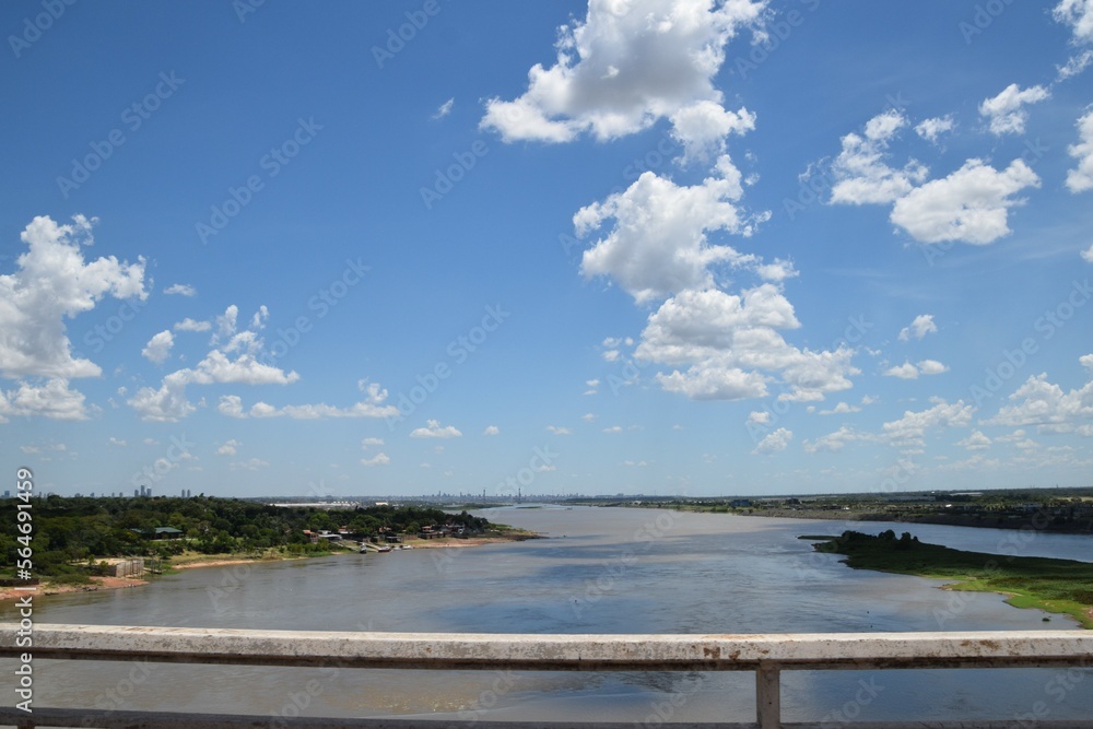 river view from a bridge with blue sky and city skyline in the horizon
