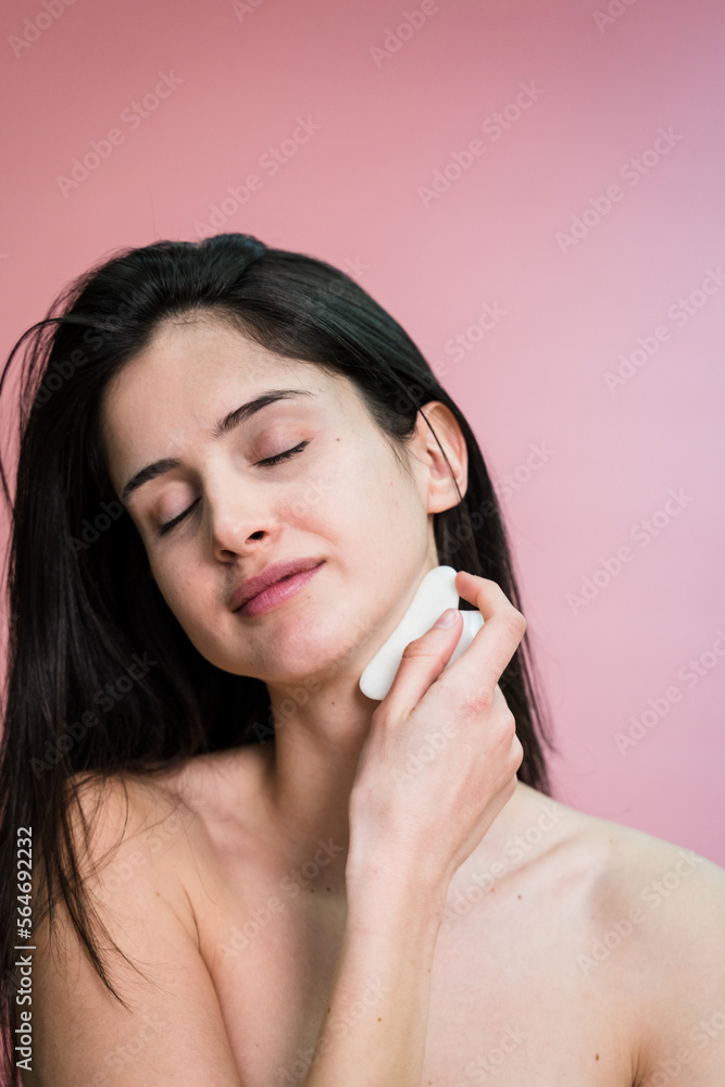 Fototapeta premium Smiling woman cleaning her skin with sponge