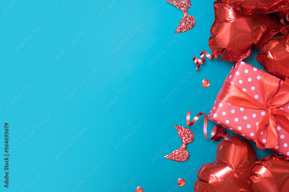 Gift box and red heart shape baloons on turquoise background. Valentines Day greeting card. Copy space