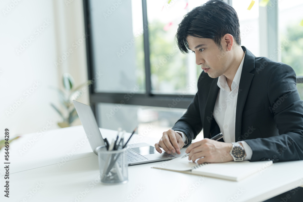 Young businessman opening a notebook View emails from customers sent. and write down the details. Young businessman opening a notebook View emails from customers sent. and write down the details.