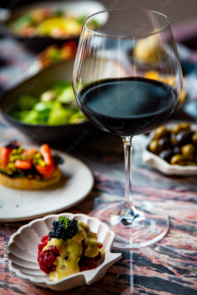 glass with red wine and wine snack set, food from spain, cheese, meat, vegetables and other appetizers on table glass with red wine and wine snack set, food from spain, cheese, meat, vegetables and other appetizers on table