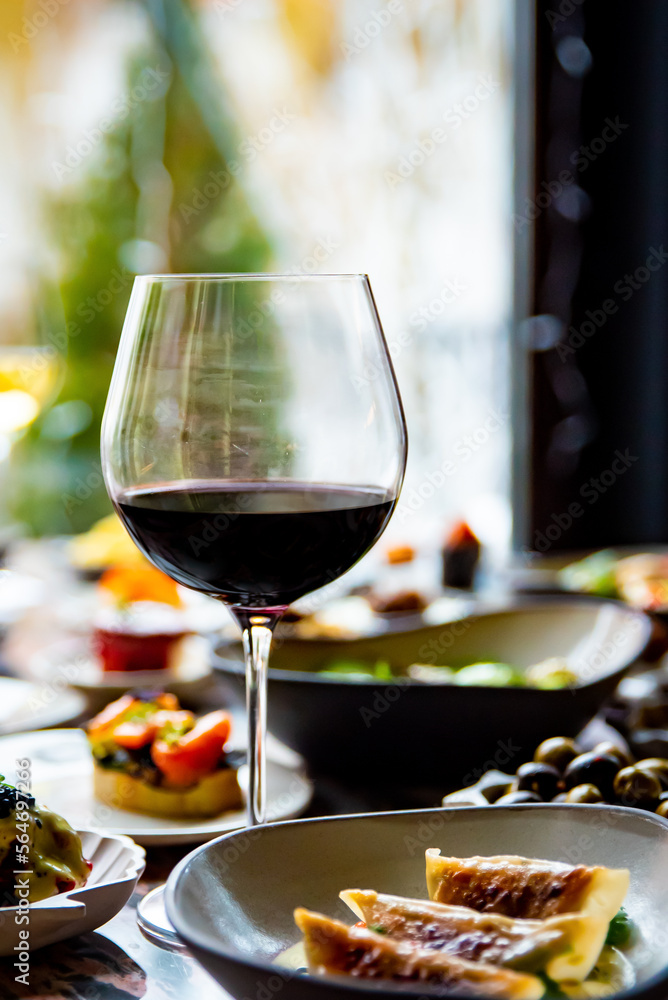 glass with red wine and wine snack set, food from spain, cheese, meat, vegetables and other appetizers on table