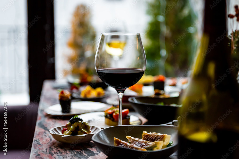 Obraz premium glass with red wine and wine snack set, food from spain, cheese, meat, vegetables and other appetizers on table