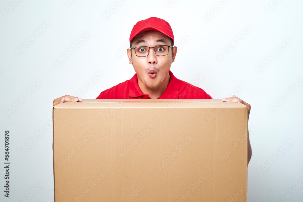 Nervous delivery guy in red uniform have lots of work as clients order from online shops, lean on cardboard box Nervous delivery guy in red uniform have lots of work as clients order from online shops, lean on cardboard box
