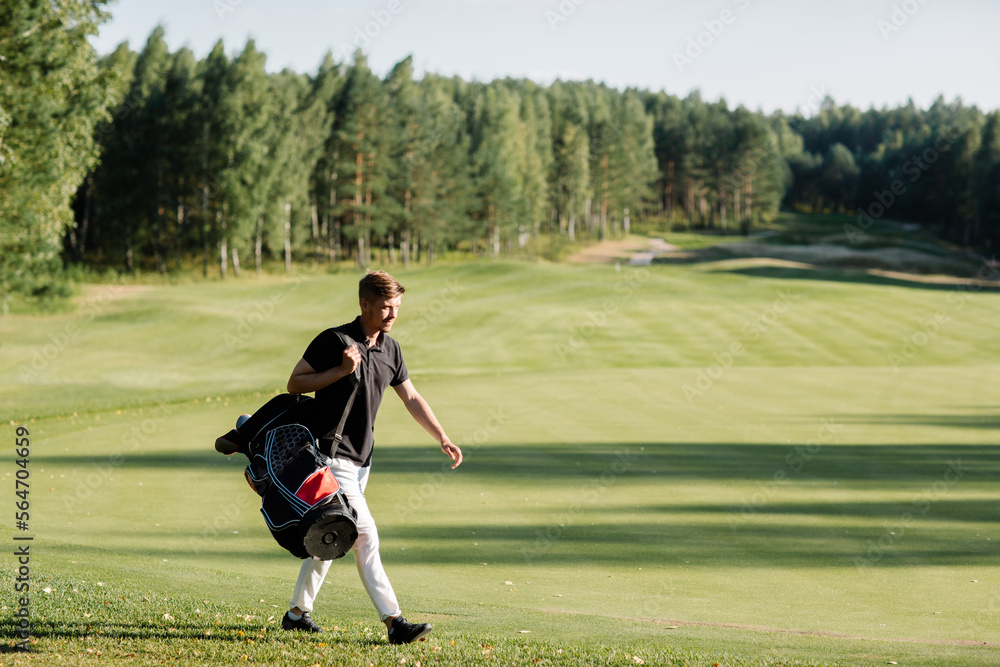 Obraz premium a golfer walks along a green field with a bag in which clubs. Caddy carries clubs. High quality photo