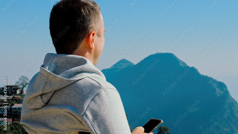 Adventurer man scrolling through social media in mountain green valley Adventurer man scrolling through social media in mountain green valley