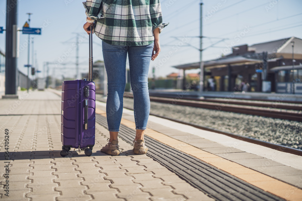 Fototapeta premium Woman with suitcase standing on train station. 