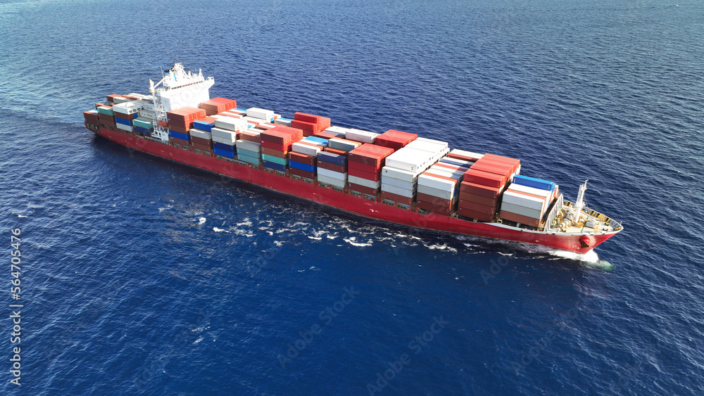 Fototapeta premium Aerial drone top down photo of huge container ship full of colourful containers cruising deep blue open ocean sea