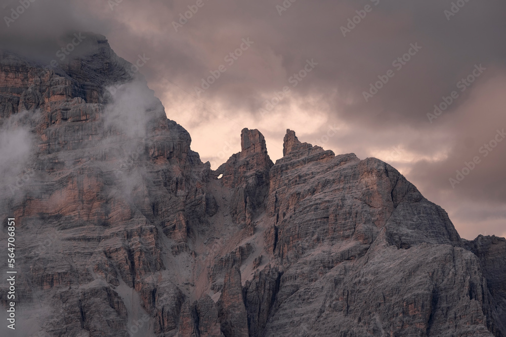 Dolomite mountain peak at sunset with low clouds