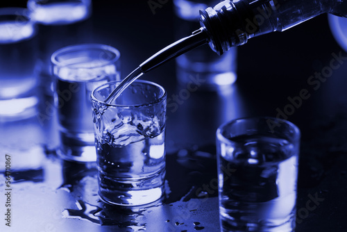 Vodka is poured into shots at the bar on the table, close-up. Party, banquet
