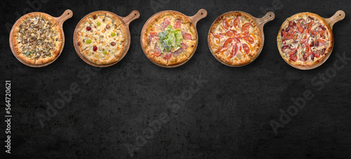Pizza in assortment, on a wooden board, on gray concrete