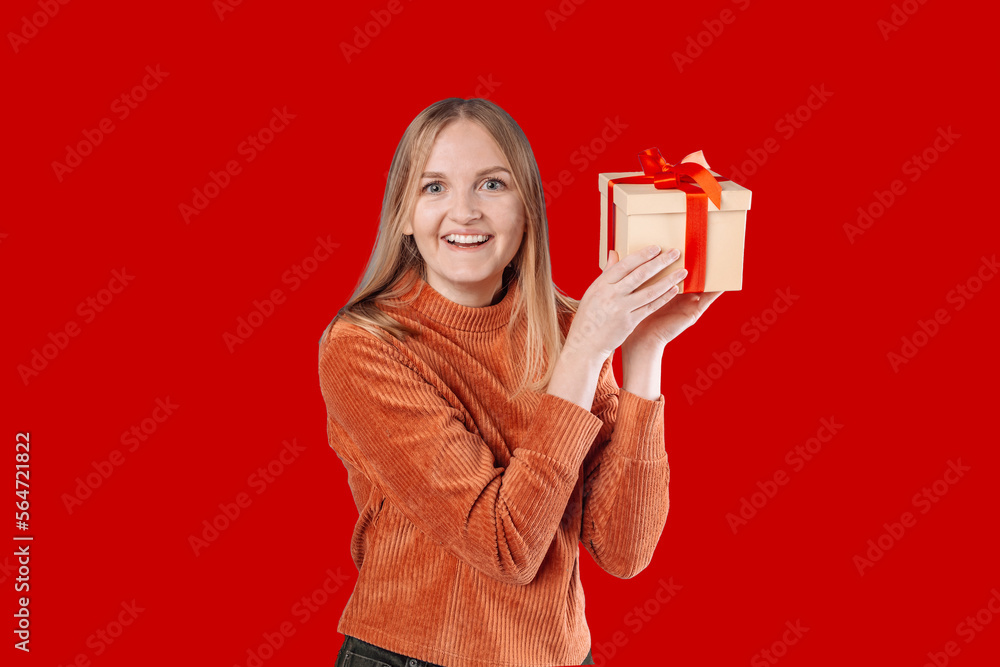 Happy young blonde woman 20s wears green denim jacket hold shake red present box with gift ribbon bow, close up, copy space. Anniversary, happy birthday, Valentine day and positive emotions. Happy young blonde woman 20s wears green denim jacket hold shake red present box with gift ribbon bow, close up, copy space. Anniversary, happy birthday, Valentine day and positive emotions.