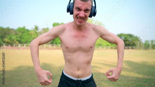 The skinny guy is screaming at the camera, headphones on his head.